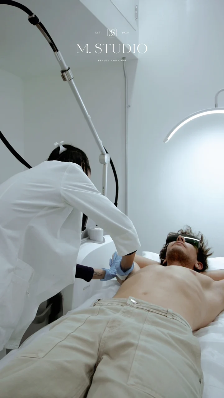Laser specialist treating a male client wearing protective eyewear at M.STUDIO